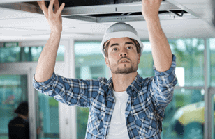 man in hard hat installing ceiling hvac 