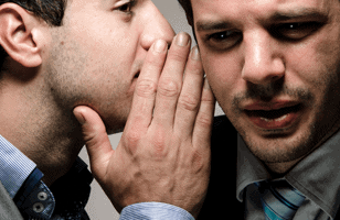 man whispering in another man's ear 