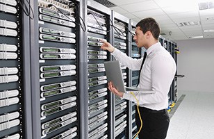 man working in a data center; holding laptop 