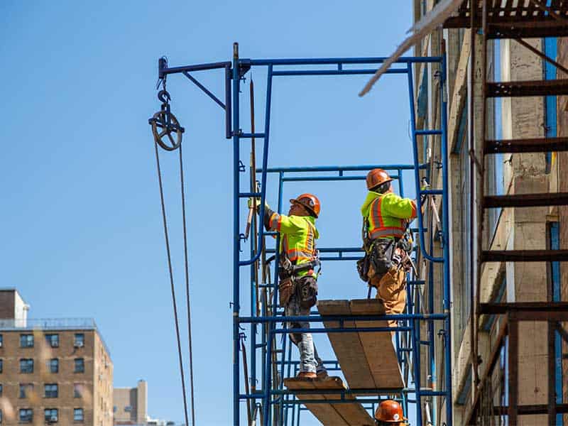 two workers working on the side of a building