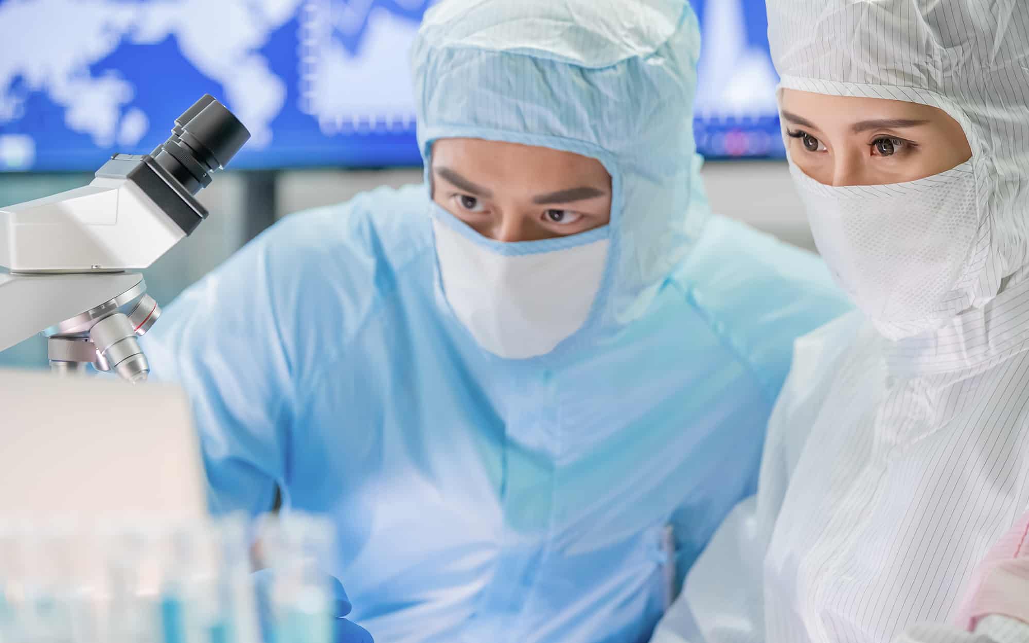 two scientists looking at a microscope