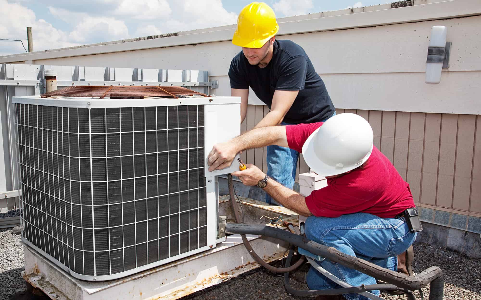 two workers working on an AC unit