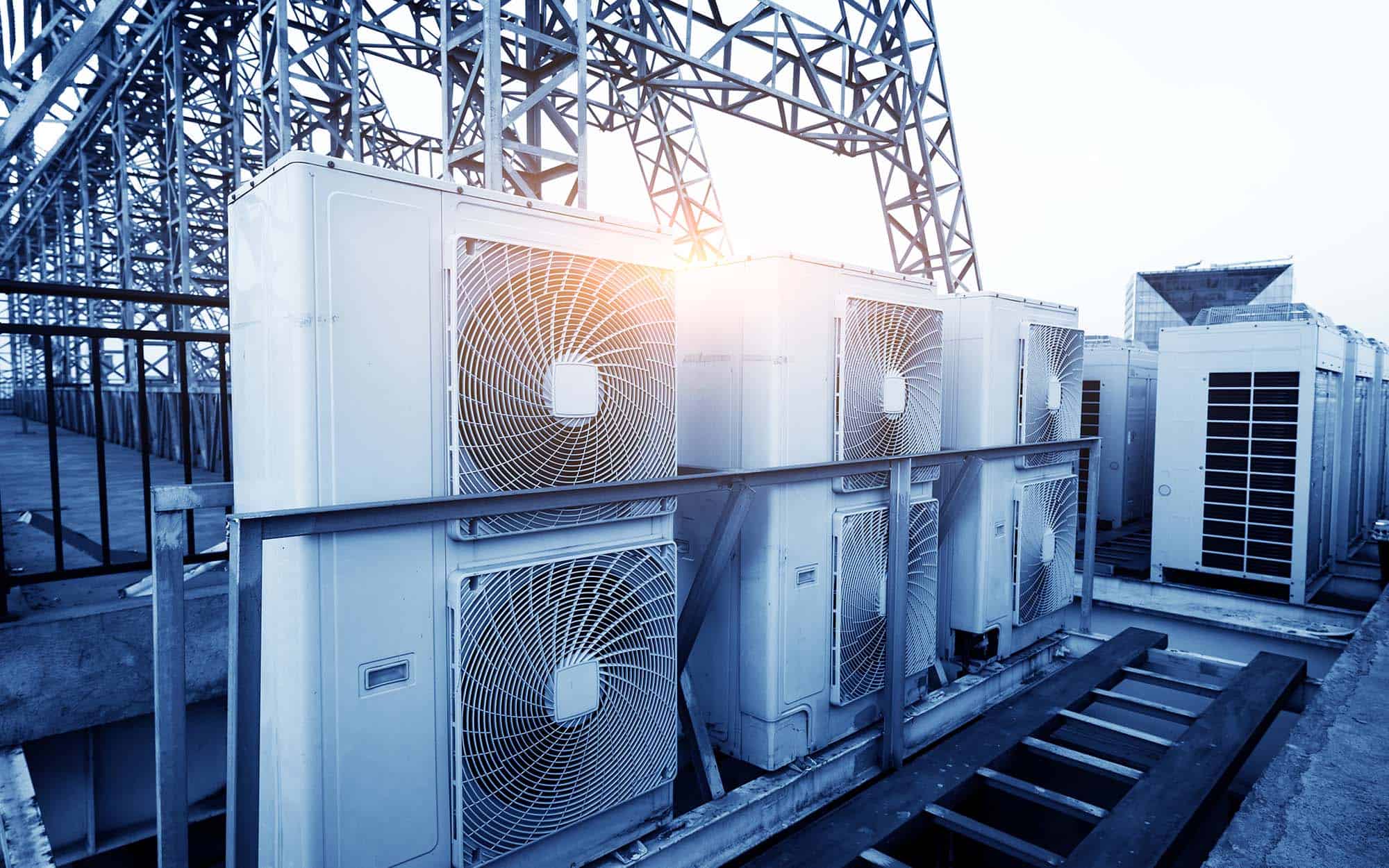 Air Conditioner Units (hvac) On A Roof Of Industrial Building With Blue Sky And Clouds In The Background | React Industries